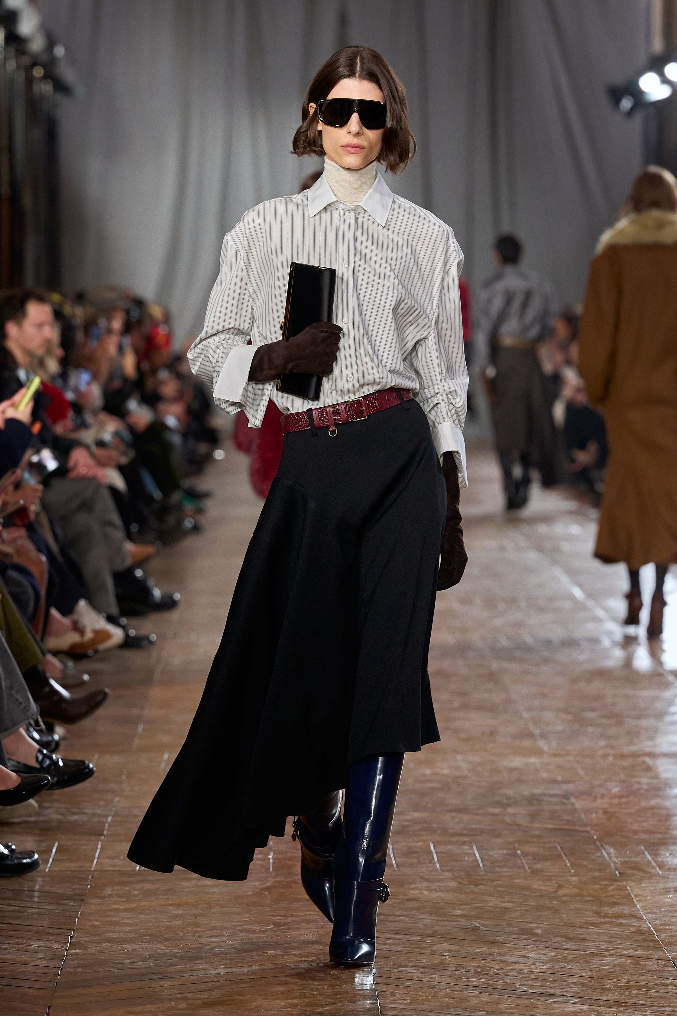 Lanvin 本季回归品牌最经典的巴黎女性气质：结构精准的西装、收腰裙装、深色羊毛套装与戏剧性大檐帽形成一种冷静而克制的奢华。柔软褶皱、细腰剪裁与高靴搭配营造出带有1930年代气息的摩登贵族感，同时通过金属亮片与垂坠流苏礼服让夜晚部分显得华丽而锋利。整场秀像一场巴黎旧贵族的时装电影，优雅却不失力量-顽石频道趋势研究